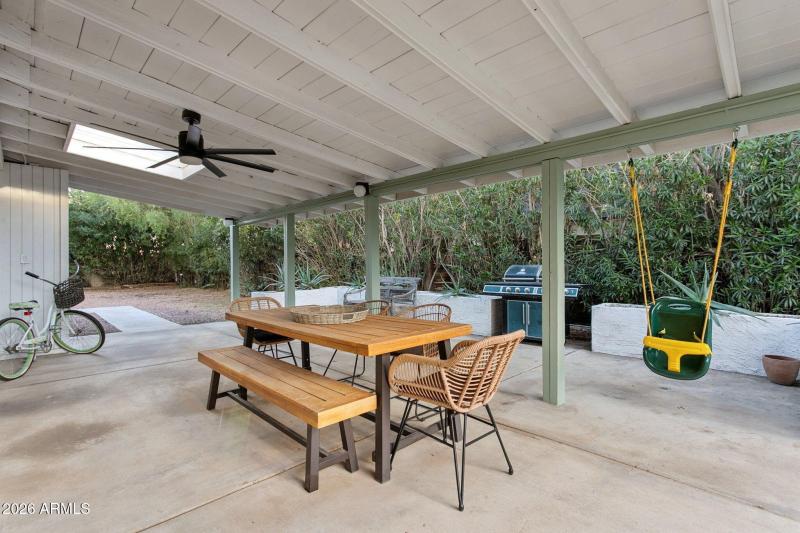 Covered rear patio surrounded by hedges